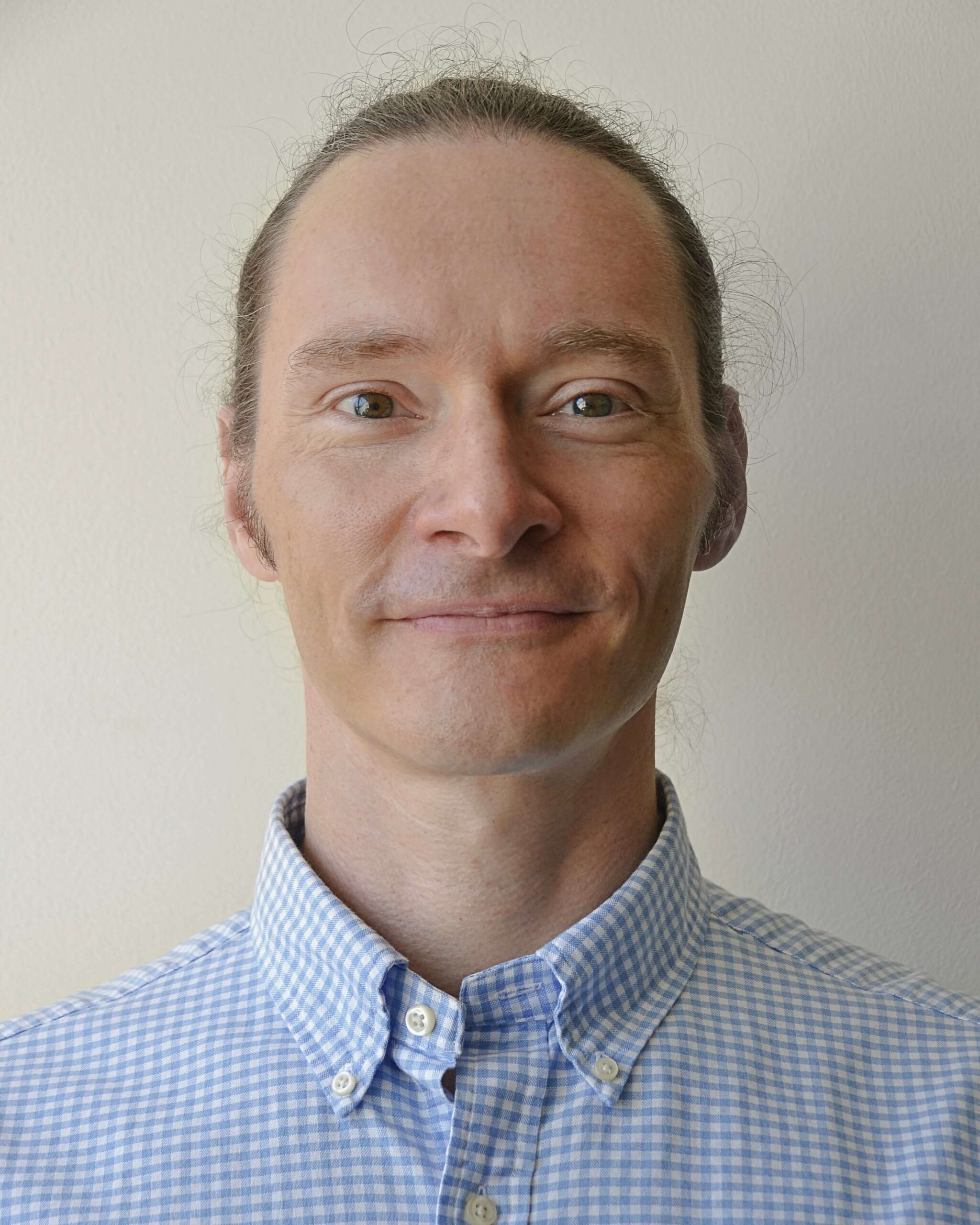 Dr. Attila Szabo wearing a blue and white checkered shirt.