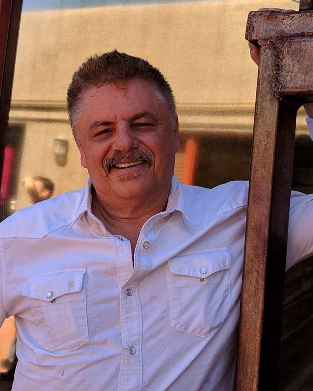 William Gazecki in a white shirt leaning against a window.