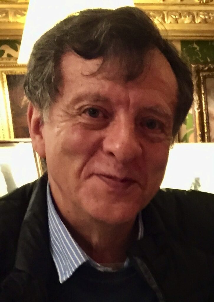 A man in a black jacket is smiling for the camera.