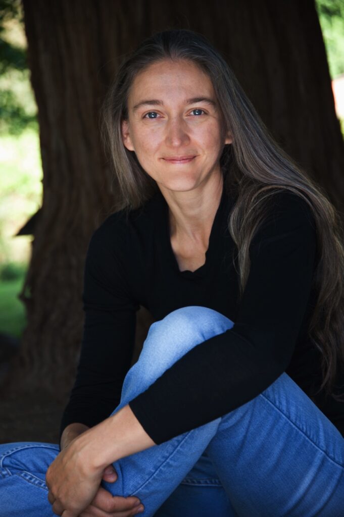 A woman sitting in front of a tree.
