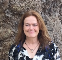 A woman standing in front of a tree.