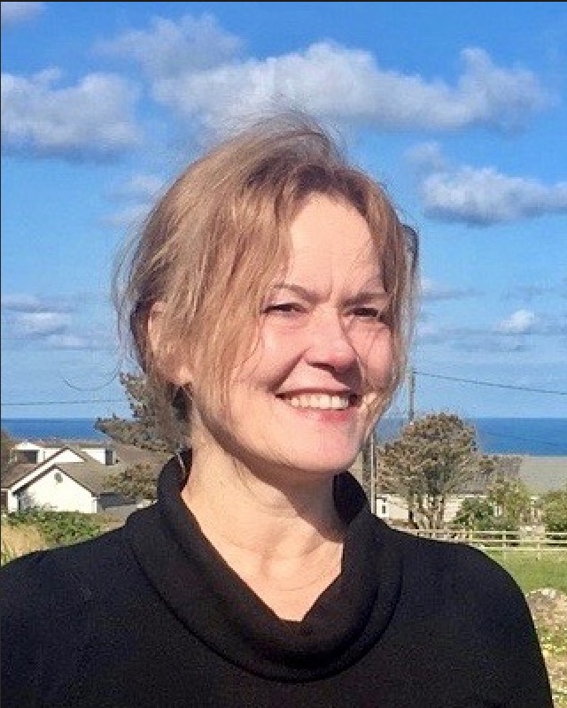 A woman smiling in front of the ocean.